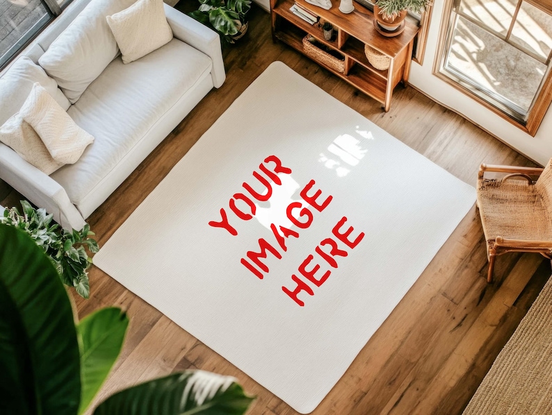 May include: A cream-coloured rectangular rug with the words "YOUR IMAGE HERE" in red. The rug is on a hardwood floor, with a white sofa, wooden furniture, and a window visible in the background. The rug is a focal point.