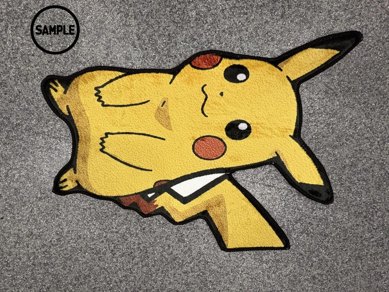 May include: A yellow Pikachu-shaped rug with black outlines and brown accents. The rug features the text "SAMPLE" in a black circle. The rug is on a grey surface.