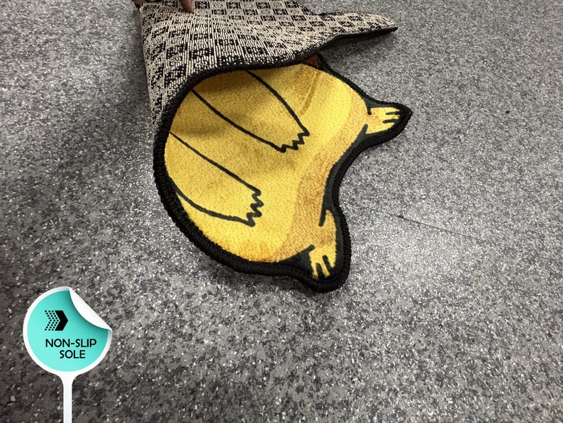 May include: A yellow rug with a black border and a cartoon bear paw design. The rug is partially rolled up, revealing a patterned underside. The rug is designed with a non-slip sole.