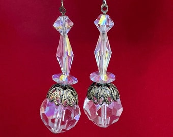 May include: A pair of crystal earrings with a gold-toned filigree design. The earrings are suspended from silver-toned hooks.
