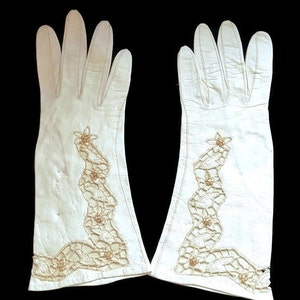 K&ouml;nnte beinhalten: Ein Paar wei&szlig;e Lederhandschuhe mit zartem wei&szlig;en H&auml;kelrand und Perlenakzenten.