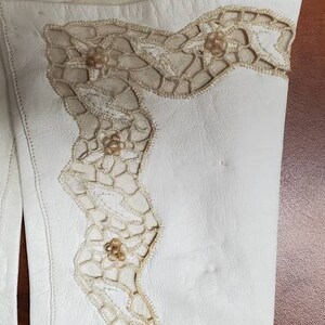 K&ouml;nnte beinhalten: Ein Paar wei&szlig;e Lederhandschuhe mit zarter Spitze und Perlenbesatz.