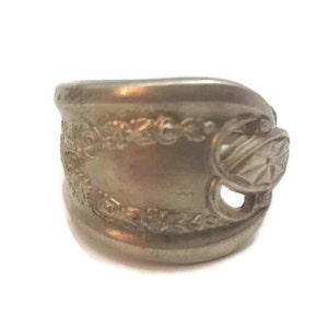 Peut inclure: Une bague en argent fabriquée à partir d'une cuillère réutilisée avec un motif orné de motifs floraux et géométriques.
