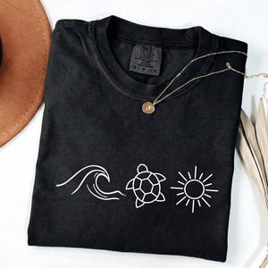 May include: A white ceramic mug with a black handle and the text "But First, Coffee" in a black, handwritten-style font. The mug is on a white surface.