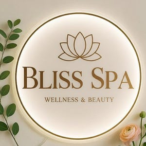 Può includere: Insegna rotonda illuminata con la scritta dorata "BLISS SPA" e un motivo a fiore di loto. Sotto, la scritta "WELLNESS & BEAUTY". L'insegna ha un bordo dorato e una luce soffusa, ideale per un centro benessere.