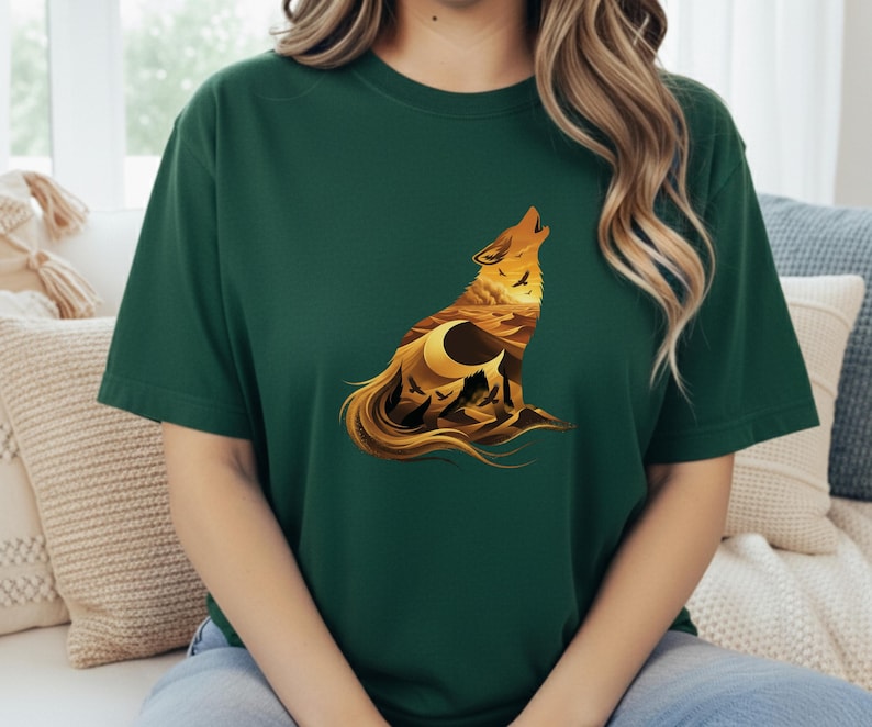 A woman wearing a dark forest green t-shirt that provides a rich, deep background for the glowing golden sun and desert mountains within the wolf.