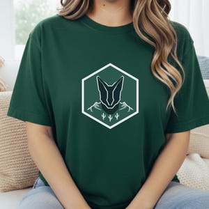 オオヤマネコバッジシャツ - アラビアカラカルミニマリストグラフィックTシャツ - レトロな山岳放浪者の紋章 - モダンな野生動物アート - 砂漠のオオヤマネコ自然Tシャツ