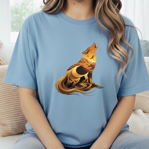 A woman in a light blue t-shirt with the desert wolf silhouette, offering a bright and airy contrast to the warm orange tones of the print.