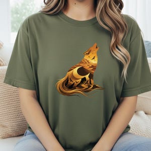 A woman wearing an olive green shirt featuring the rugged western landscape wolf silhouette, creating a natural, outdoorsy look.