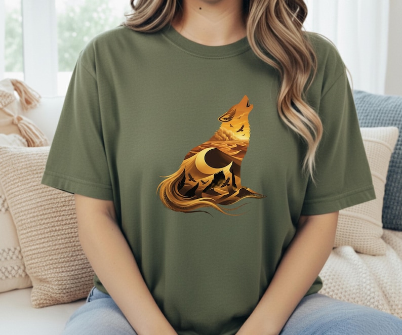 A woman wearing an olive green shirt featuring the rugged western landscape wolf silhouette, creating a natural, outdoorsy look.