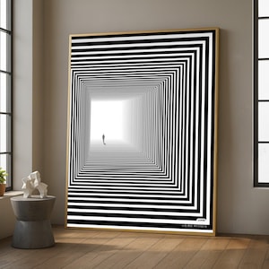 May include: A framed art print depicting a black and white optical illusion of a receding square tunnel. A small silhouette of a person stands at the end of the tunnel, illuminated by light. The artwork is in a gold frame and is displayed in a room with natural light.