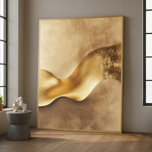 以下が含まれることがあります： 金と茶色の色合いの抽象芸術作品。 質感のある外観の、流れるような多層の形が描かれており、金色のフレームに収められています。 自然光が入る部屋に飾られています。