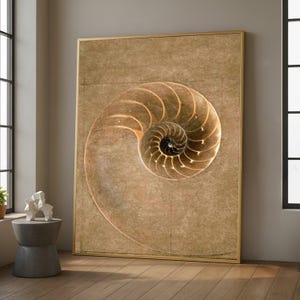 May include: Large framed artwork depicting a nautilus shell's spiral design. The shell is illustrated in gold and brown tones against a textured, tan backdrop. The artwork is enclosed in a gold frame, adding to its elegant appearance. The artwork is displayed indoors.