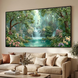 Può includere: Un dipinto di paesaggio incorniciato raffigura una serena scena di foresta con cascate, un lago turchese e una vegetazione lussureggiante. Gli uccelli sono in volo. L'opera d'arte è esposta sopra un divano beige con cuscini decorativi.