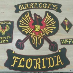 May include: A set of embroidered patches featuring a large central phoenix emblem with red and yellow details, a top rocker patch reading WARLOCKS, a bottom rocker patch reading FLORIDA, a side patch reading FOREVER LIFER, and a WFFW patch.