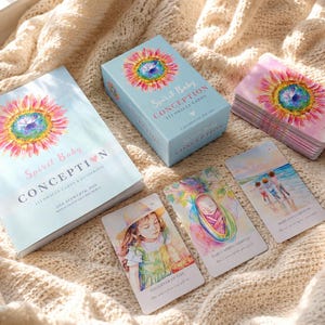 Puede incluir: Un juego de cartas oráculo Spirit Baby Conception que incluye una caja azul claro, una guía y un mazo de cartas. La caja y la portada del libro muestran una colorida ilustración de un girasol y el texto Spirit Baby CONCEPTION. Tres cartas individuales muestran imágenes al estilo acuarela de un niño, un bebé envuelto y tres personas caminando por una playa.