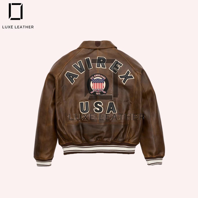 Puede incluir: Chaqueta de cuero marr&oacute;n con la palabra "AVIREX" arqueada en la espalda en letras blancas. Debajo, un parche con las palabras "ALL AMERICANS" y "USA". La chaqueta tiene un ribete a rayas blancas y marrones.