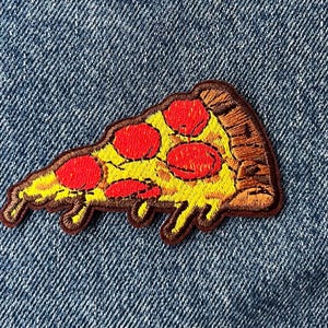 May include: An embroidered patch shaped like a slice of pepperoni pizza. The design features a yellow melted cheese base with bright red circular pepperoni slices and a brown crust edge, all outlined with dark brown thread stitching.
