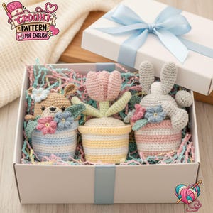 Peut inclure: Une boîte cadeau blanche contenant trois objets crochetés : un ours dans un pot rayé bleu et blanc, une tulipe rose dans un pot rayé jaune et blanc, et un lapin gris dans un pot rayé rose et blanc, entourés de confettis en papier colorés.