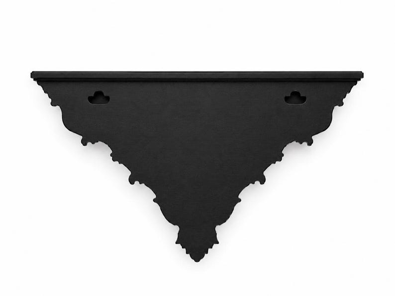 May include: A matte black wall shelf featuring a flat top surface and a decorative, triangular-shaped bracket with intricate scalloped edges. The back panel includes two pre-cut keyhole slots for mounting purposes, providing a stable structure.