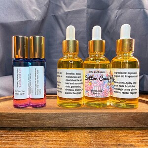 Puede incluir: Una bandeja de madera contiene varias botellas peque&ntilde;as de vidrio con aceite para cut&iacute;culas. Las botellas tienen tapas y cuentagotas dorados. Las etiquetas dicen "Cotton Candy" y "Cuticle Oil". Los aceites son para hidratar y nutrir las u&ntilde;as y cut&iacute;culas.