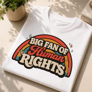 Könnte beinhalten: Ein weißes T-Shirt mit Rundhalsausschnitt und einem grafischen Design eines mehrfarbigen Regenbogens in Rot, Orange, Gelb und Blaugrün. Der Text "BIG FAN OF Human RIGHTS" ist in einer fetten Retro-Schriftart in der Mitte des Regenbogens gedruckt.