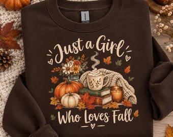 May include: A dark brown crewneck sweatshirt featuring a graphic print with the text Just a Girl Who Loves Fall. The design includes a mug of coffee, stacked books, pumpkins, autumn leaves, a candle, and a bouquet of flowers in a jar.