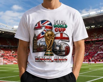 May include: A white t-shirt featuring a graphic design with the text FIFA WORLD CUP 2026 ENGLAND. The design includes a gold trophy, the Union Jack, the English flag, Big Ben, a red double-decker bus, Tower Bridge, and a red telephone booth.