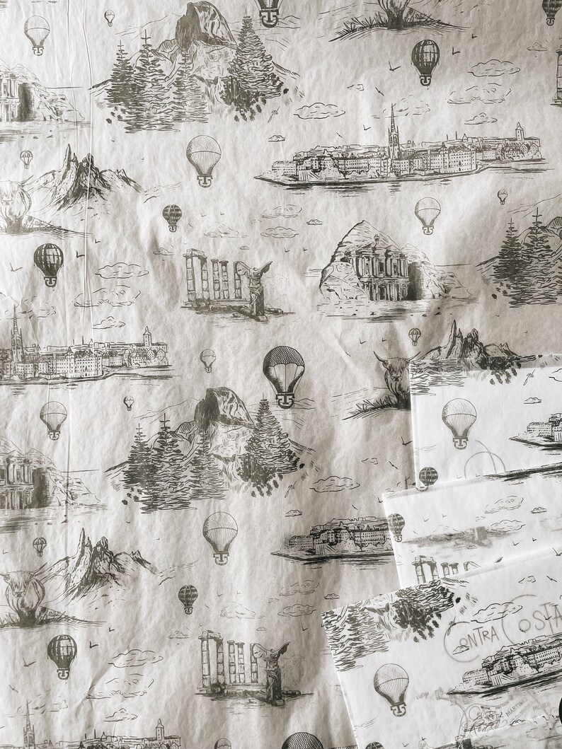 May include: A white background with a repeating pattern of black and white illustrations of hot air balloons, mountains, and buildings. The pattern is reminiscent of a vintage travel poster.