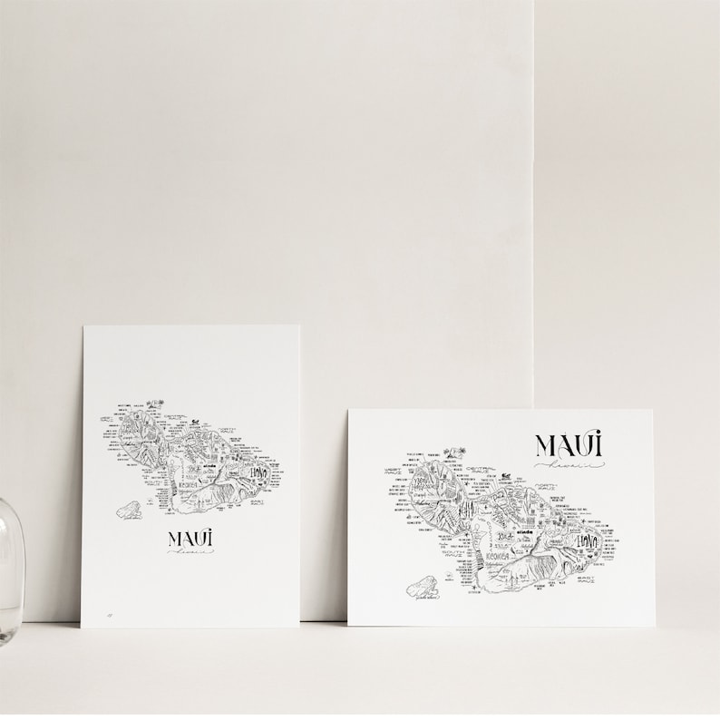 May include: Two black and white prints of a hand-drawn map of Maui, Hawaii. The prints are on white paper with a white background. The text "MAUI" is written in black at the bottom of each print.