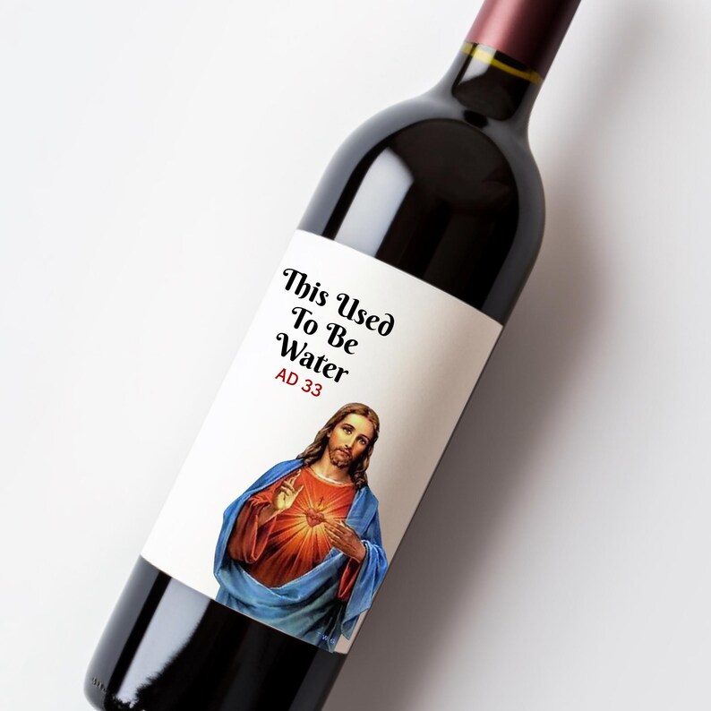 May include: A wine bottle with a label featuring an image of Jesus and the text "This Used To Be Water AD 33". The bottle is filled with red wine and has a dark burgundy neck.