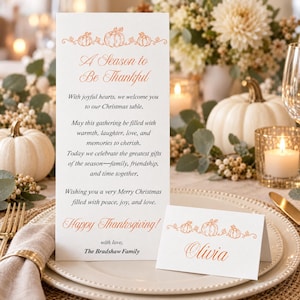 May include: A white vertical menu card and a matching folded place card, both featuring orange pumpkin illustrations and elegant script text. The menu reads A Season to Be Thankful, followed by a holiday message and The Bradshaw Family signature.