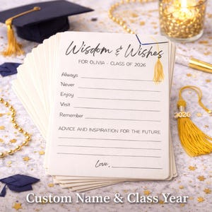 May include: A pile of ivory graduation advice cards, inscribed with "Wisdom & Wishes" and "FOR OLIVIA - CLASS OF 2026". The cards offer space for advice. A gold tassel and miniature graduation cap are also visible.
