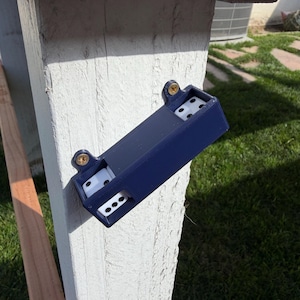 May include: A navy blue dice holder is mounted on a white wooden post with two gold screws. The holder contains white dice with black dots. The holder is rectangular with a slot for the dice to be visible.