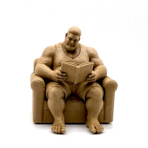 May include: A light brown monochromatic figurine of a muscular person with a beard, wearing a tank top and shorts, sitting in an armchair while reading an open book. The figure has a textured surface and is depicted in a seated, relaxed position.