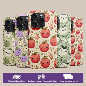 May include: Five phone cases with apple designs. The cases feature smiling apples in red, green, and purple, with floral accents on a cream background. The text "AVAILABLE NOW!" is visible.
