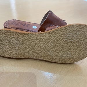 "A pair of artisan handcrafted Moroccan leather flat sandals featuring a classic -style strap. Made from high-quality natural grain leather with meticulous hand-stitching, shown from a top-down view on a neutral surface."