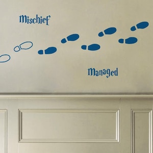 Peut inclure: Un ensemble d'autocollants muraux représentant des empreintes de pas bleu foncé et le texte "Mischief" et "Managed" dans une police de style gothique. Le motif comprend une série d'empreintes de chaussures pleines et contournées.