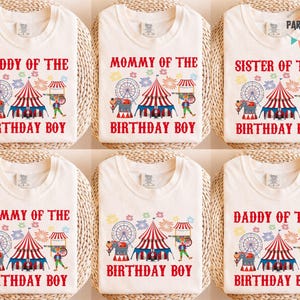 May include: Off-white t-shirts with circus-themed graphics and text. Designs include "Daddy of the Birthday Boy," "Mommy of the Birthday Boy," and "Sister of the Birthday Boy." Each shirt features a red and white striped circus tent, a Ferris wheel, and an elephant.