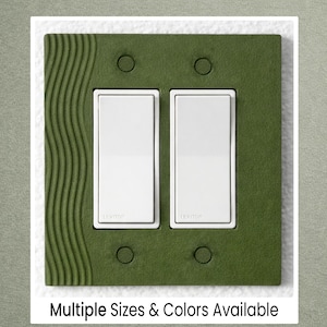 May include: A green double light switch cover with a textured wave design on the left side. The cover has two white light switches and the text "Multiple Sizes & Colors Available" at the bottom.