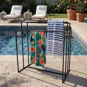 Puede incluir: Un toallero de metal negro con marco rectangular que sostiene dos toallas. Una toalla presenta un vibrante estampado tropical con tucanes e hibiscos, mientras que la otra muestra un diseño clásico de rayas horizontales en azul y blanco.
