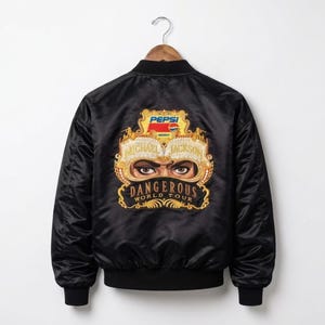 Può includere: Giacca bomber nera con colletto, polsini e orlo a coste. La parte posteriore presenta un logo Pepsi dorato e rosso sopra una grafica dorata degli occhi di Michael Jackson e le parole "DANGEROUS WORLD TOUR".
