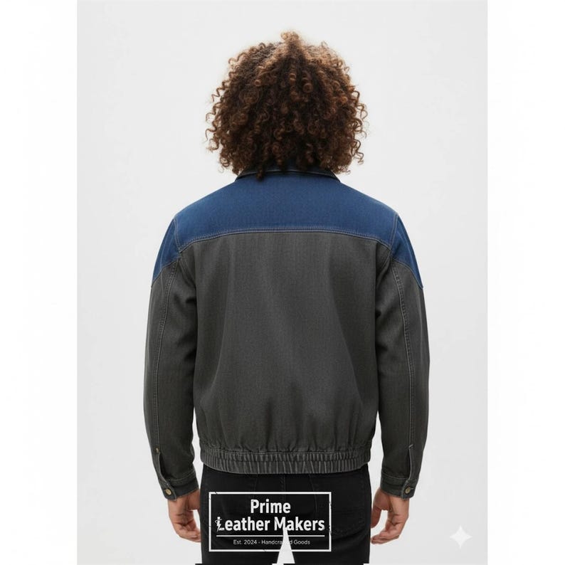 May include: A denim jacket with a two-tone design. The upper portion of the jacket is a medium blue, while the lower portion is a dark gray. The jacket has a button closure and a ribbed hem. The text "Prime Leather Makers" is visible.