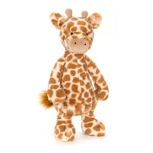 May include: A plush giraffe toy with a soft, textured body. The giraffe features a brown and white spotted pattern, a tan snout, small brown horns, and a fluffy tail. The toy is standing upright on a white background.