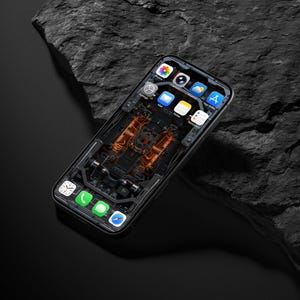 May include: A smartphone with a black frame and a screen displaying a digital wallpaper of internal mechanical components in orange and black. The interface shows standard app icons including Photos, Camera, Settings, Mail, Notes, App Store, Clock, Phone, Messages, and Safari.