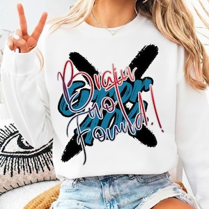 May include: White sweatshirt with the text "Brain No Found!" in blue, red, and black. The text is stylized with a gradient effect and is crossed out with two black brush strokes. The sweatshirt is paired with denim shorts.