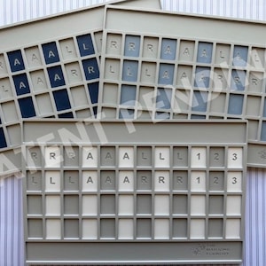 Op de afbeelding: Drie rechthoekige lichtgrijze plastic spelbordhouders met rastervakken. Elke houder heeft in reli&euml;f gedrukte letters R, A, L en cijfers 1, 2, 3 in de bovenste rijen. De onderste rijen bevatten lege vakken. Het Mahjong Foundry logo is rechtsonder zichtbaar.