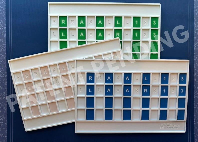 Op de afbeelding: Drie rechthoekige witte kunststof organizers met rastervakken. Elke organizer heeft gekleurde inzetstukken in groen, blauw of beige. De inzetstukken zijn bedrukt met de letters R, A, L en de cijfers 1, 2, 3 in een herhalend patroon.
