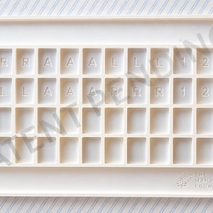 May include: Off-white Mahjong tile tray with multiple square compartments. The tray has the text "R, A, L, 1, 2, 3" in some of the compartments. The bottom right corner has the text "THE MAHJONG FOUNDRY".