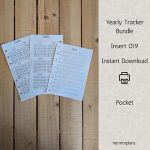 May include: Three white paper inserts with the word "Tracker" printed on them, arranged on a wooden surface. The inserts include calendar layouts and a habit tracker. Text on the right side reads "Yearly Tracker Bundle, Insert 019, Instant Download, Pocket."